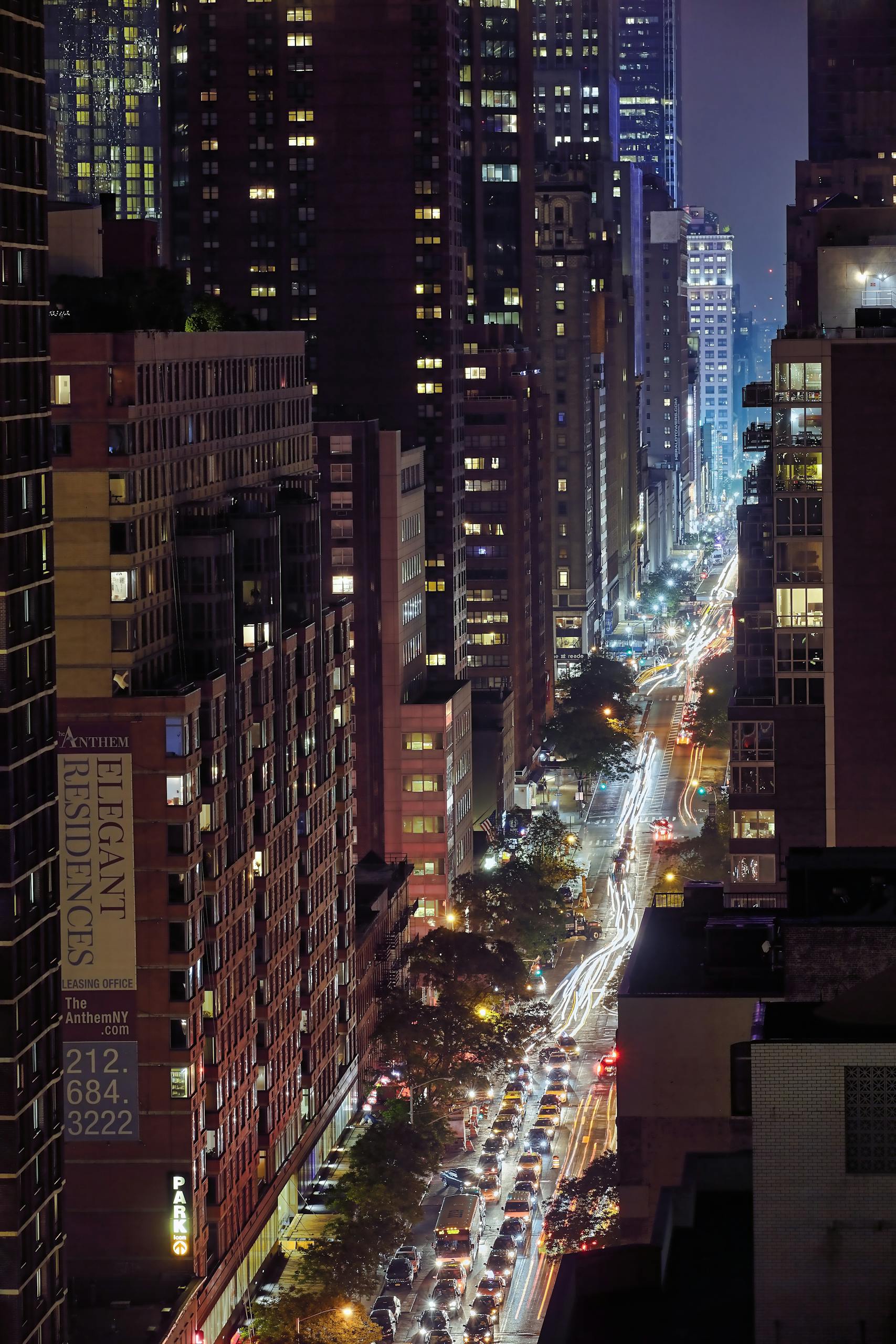 Stunning cityscape of New York at night with illuminated skyscrapers and light trails.